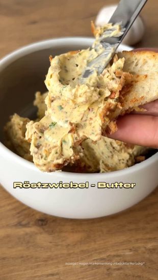 Ein Messer streicht Röstzwiebelbutter auf eine Scheibe Brot, im Hintergrund eine Schale mit der Butter. Der Text auf dem Bild lautet Röstzwiebel - Butter.