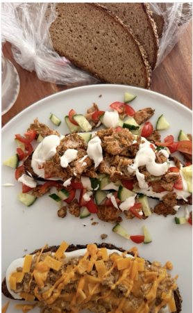 Zwei belegte Brotscheiben auf einem Teller: eine mit angebratenem Hackfleisch, Zwiebeln, Pfeffer, cremiger Southwest-Soße, Kochsahne und geschmolzenem Cheddar; die andere mit veganem Gyros aus Hähnchenersatz, frischen Gurken- und Tomatenscheiben sowie würziger Soße auf getoastetem Brot.